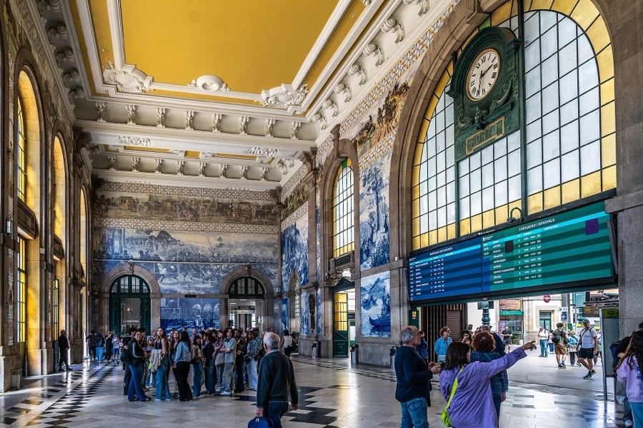 The hall of São Bento station in Porto, its walls covered in blue and white tiles under a yellow ceiling